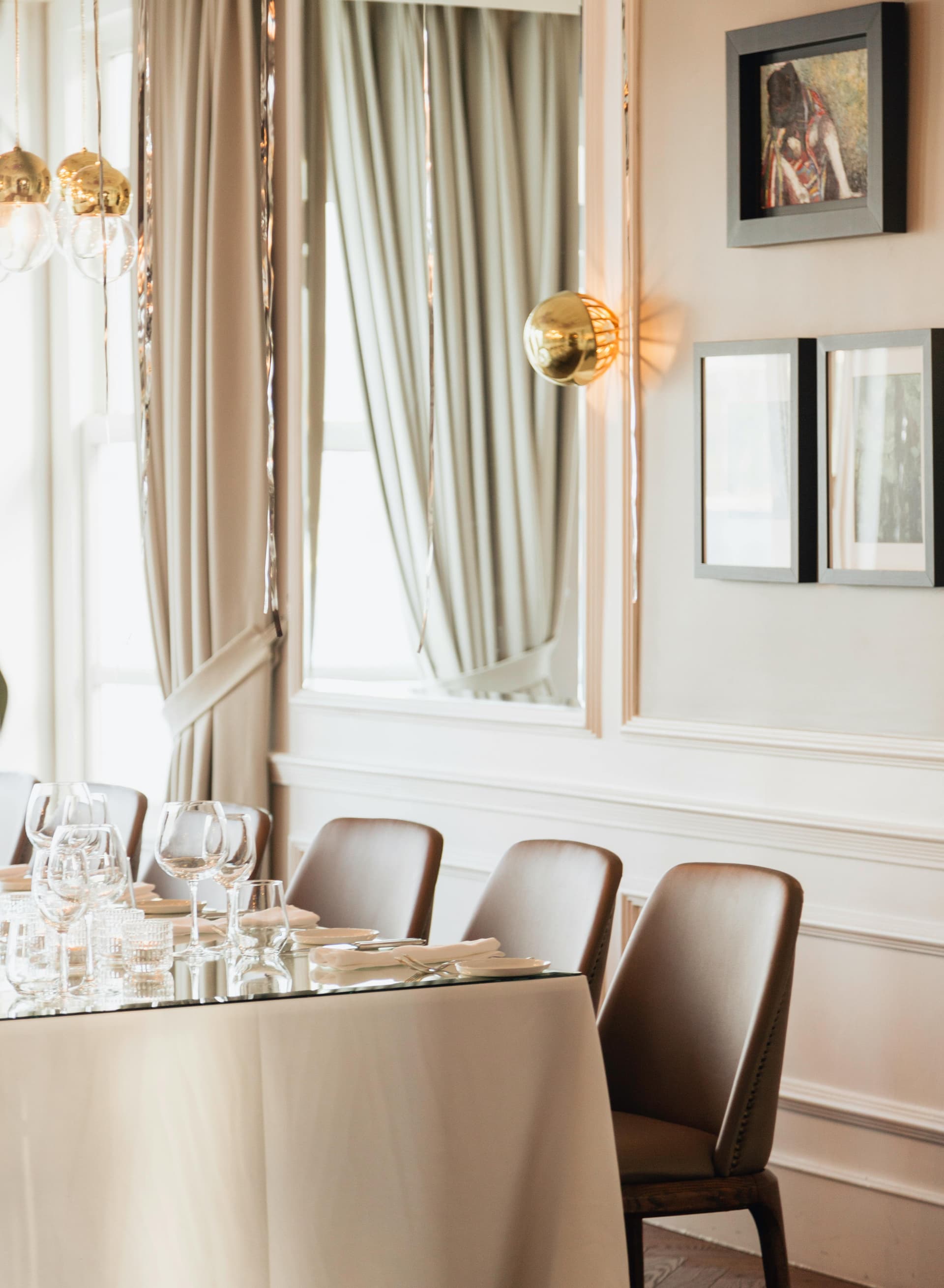 Elegant private dining room with crystal glassware, leather chairs, and gold pendant lighting in an intimate fine-dining setting